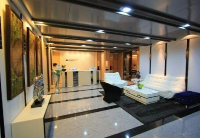 Lounge area with white leather sofas and a glass coffee table under a recessed ceiling.