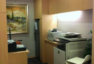 Compact business center with wood cabinetry, a photocopier, and a high stool.