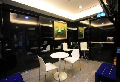 Breakout area with white tables and chairs against a sleek black paneled wall.