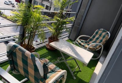 Outdoor balcony lounge with artificial grass, checkered chairs, and a small table.