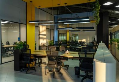 Bright coworking space with wooden desks, potted plants, and sleek glass partitions.