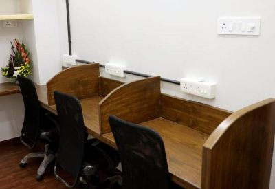 Row of wooden individual workstations with black mesh office chairs.