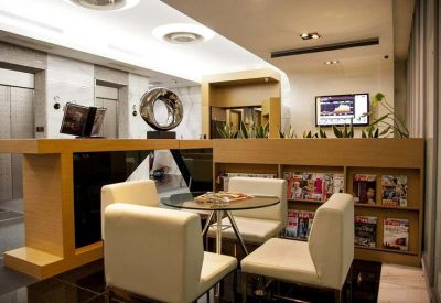 Reception area with a wooden desk, white club chairs, and a magazine rack.