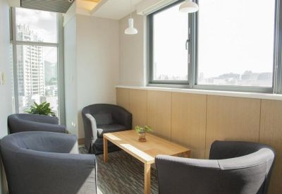 Lounge area featuring four grey armchairs around a light wood coffee table.