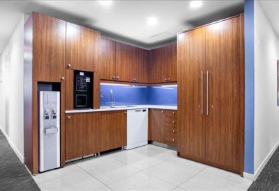 Modern breakroom kitchen with wood-finish cabinetry, blue backsplash, and built-in appliances.