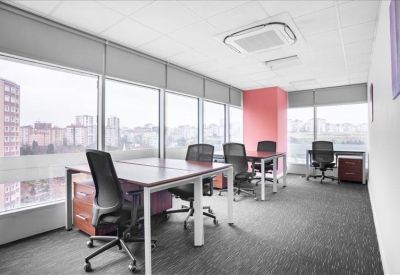 Bright corner office with pink feature wall, modern desks, and panoramic city views.
