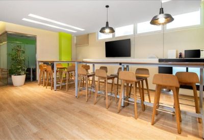Communal breakout area with high wooden bar stools, a long counter, and a television.