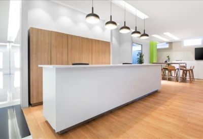 Modern white reception desk with stylish hanging pendant lights and wood-panelled storage.