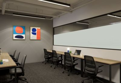 Minimalist shared workspace with long wooden desks and ergonomic black chairs.
