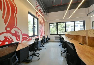 Bright office space with a large red and white wave mural, wooden desks, and ergonomic black chairs.