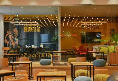 Coworking area featuring warm lighting, tiered wooden seating, and glass partitions with artistic graphics.