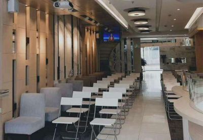 Casual presentation room with rows of white folding chairs and wood-paneled walls.