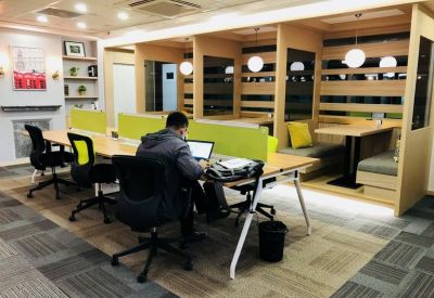 Bright coworking space featuring a long wooden desk and soundproof semi-private booths.