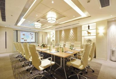 Spacious boardroom with a large wooden table and cream-colored leather chairs.