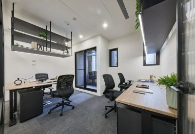 Private four-person office suite with light wood desks and black ergonomic chairs.