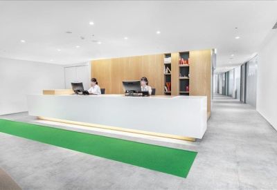 Minimalist white reception desk with a vibrant green floor runner.
