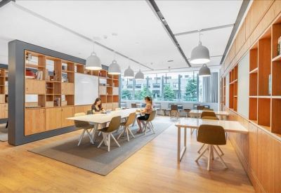 Spacious coworking area with long communal tables and modern pendant lighting.