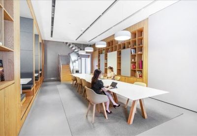 Bright library-style workspace with wooden bookshelves and a long white desk.