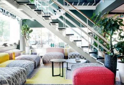 Modern breakout area featuring a white staircase, colorful pouf seating, and potted trees.