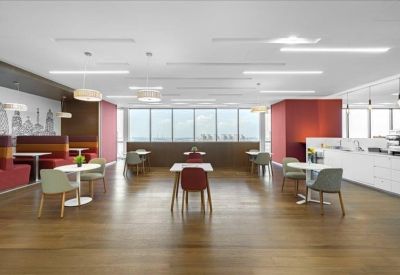Spacious communal breakout area with wooden floors, dining tables, and a cafe-style counter.