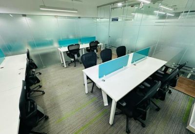 Bright open-plan workspace featuring multiple rows of white desks and black mesh chairs.