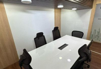 Modern meeting room with a sleek white table, black executive chairs, and wood-paneled ceiling.