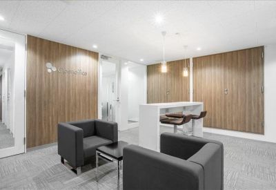 Communal lounge area with grey armchairs and wood-paneled walls.