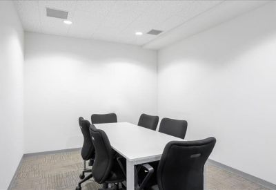 Bright white meeting room featuring a rectangular table and six black ergonomic chairs.