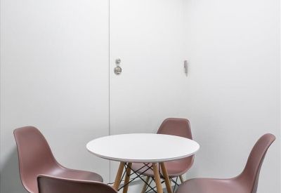 Small meeting area with a round white table and four mauve-colored chairs.