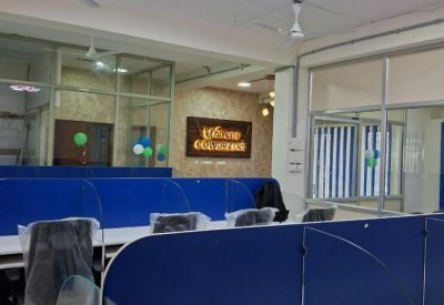 Bright coworking hall showing white desks with blue partitions and glass dividers.