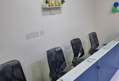 Modern open-plan workspace with white desks, blue privacy screens, and decorative wall plants.