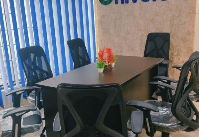 Close-up of a meeting table with black mesh chairs and blue and white vertical blinds.