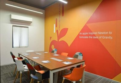 Bright meeting room with a vibrant orange wall and wood table.