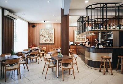Stylish café and bar area with warm wood paneling, counter seating, and small dining tables.