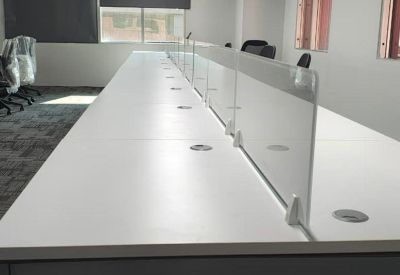 Modern open-plan office desk rows with decorative balloons hanging from a linear light fixture.