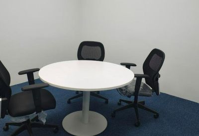Small meeting area with a round white table and four black mesh office chairs.