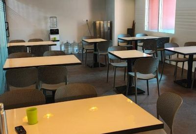 Vibrant communal dining area with several tables, grey chairs, and yellow balloon decorations.