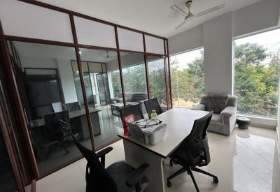 Bright private meeting room with a white desk, ergonomic chairs, and a glass-walled partition.