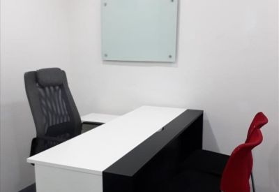 Compact meeting space featuring a white and black desk, two red chairs, and a whiteboard.