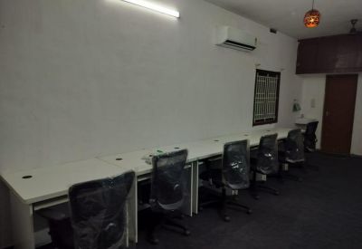 Open-plan office with a long white communal desk and ergonomic mesh chairs at 4B, 3rd Street, Raja Nagar, Ganapathy.