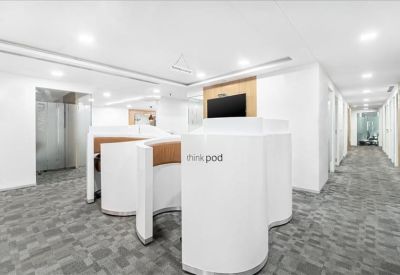 Modern coworking area with white privacy pods and grey patterned carpet.