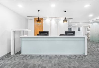 Spacious white reception area featuring a minimalist front desk and hanging pendant lights.