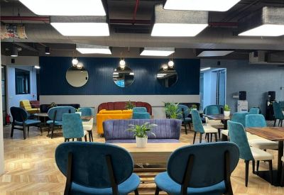 Spacious communal lounge with colorful velvet seating, wooden floors, and circular wall mirrors.