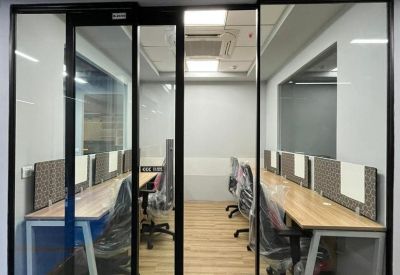 Glass-enclosed office suite with multiple wooden desks and black chairs.