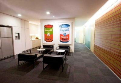 Lounge area featuring black leather seating and colorful pop art soup can paintings.