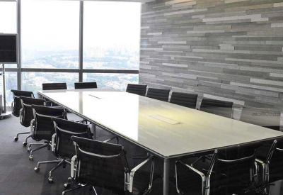 Spacious boardroom with a long white table, black chairs, and a textured stone feature wall.