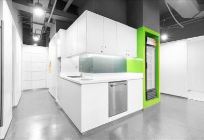 Minimalist white kitchen area with a built-in dishwasher and green wall accent.