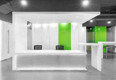 Sleek, white reception desk with green glass accents and modern lighting.