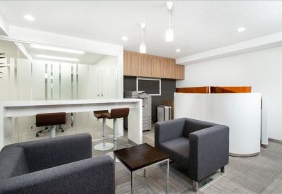 Modern communal breakout area with high-top seating and grey armchairs.