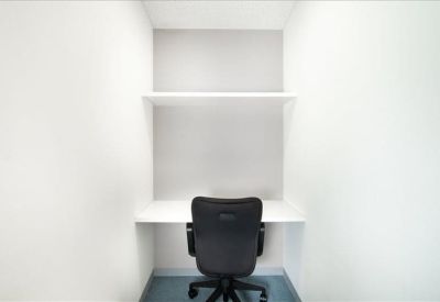 Compact private workstation with white desk and black ergonomic chair.